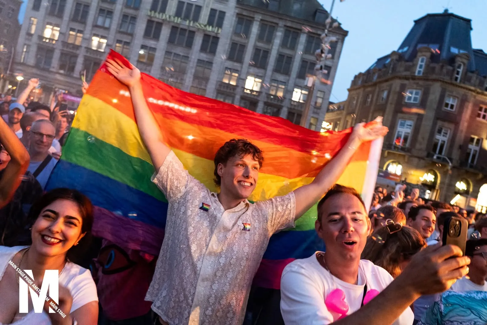 Visitors waving a large rainbow flag at golden hour, MainStage Pride Amsterdam 2026